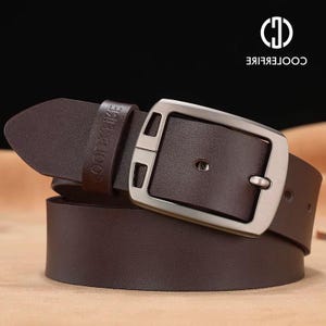 May include: A brown leather belt with a silver buckle. The belt loop is embossed with the brand name "COOPERLIKE". The buckle is rectangular and has a single pin closure.
