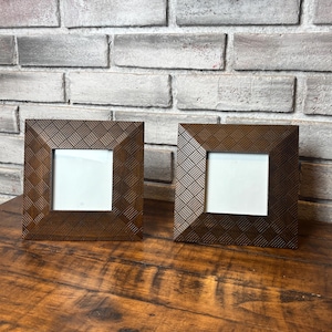 May include: Two square picture frames with a dark brown finish and a textured, woven-style pattern on the wide borders. Each frame features a central white display area for a photograph, showcasing a consistent design and matching wooden construction.