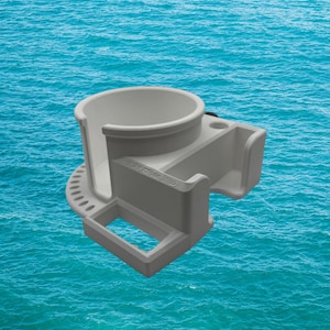May include: A grey plastic cup holder with a circular top, a rectangular opening, and a small compartment. The cup holder has a series of small holes around the base and is set against a blue water background.