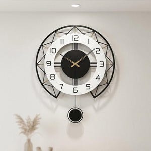 Peut inclure: Une horloge murale ronde dotée d'un cadre extérieur en métal noir au design géométrique, d'un cadran circulaire blanc avec des chiffres arabes noirs et d'un centre noir uni. L'horloge comprend des aiguilles dorées et un pendule noir suspendu.