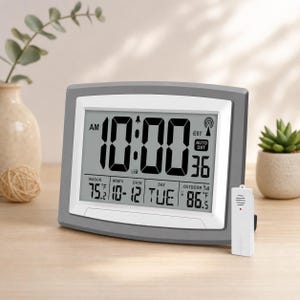May include: A digital clock with a gray frame displays the time as 10:00 AM. It also shows the indoor temperature at 75.2°F and the outdoor temperature at 86.5°F. The date is 10-12, Tuesday. A white wireless sensor is on the right.