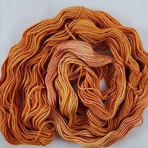May include: A skein of orange and peach colored yarn. The yarn is soft and fluffy, and it is perfect for knitting or crocheting.
