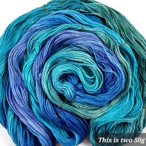 May include: Two skeins of blue and green gradient yarn, each weighing 50 grams. The yarn is wound into a ball shape and is ready for knitting or crocheting.