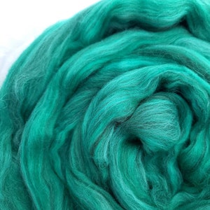 May include: A close-up of a teal blue wool roving. The roving is soft and fluffy, and it is perfect for spinning or felting.