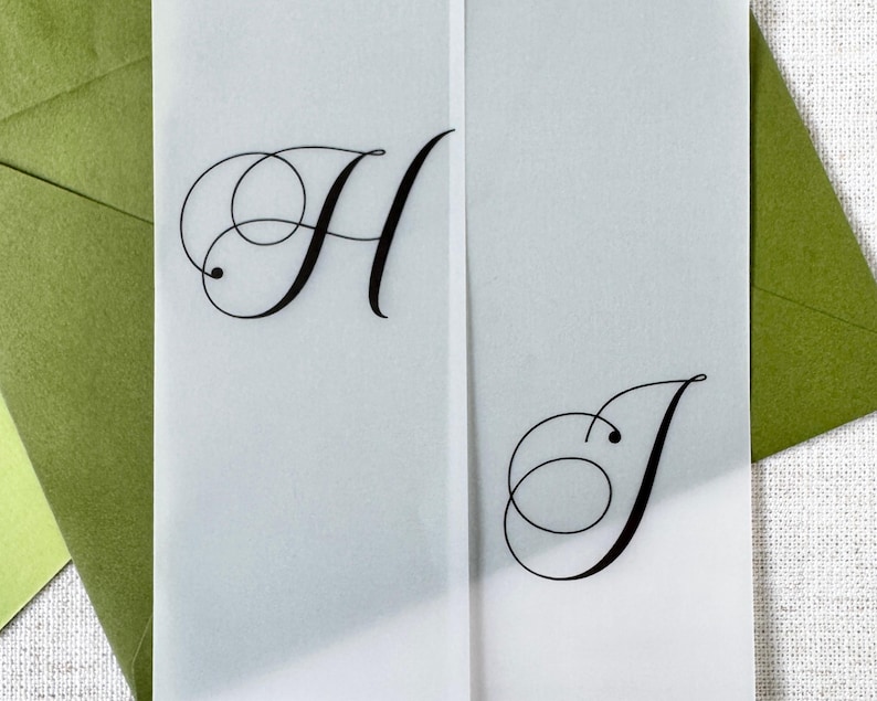 Puede incluir: Primer plano de una invitaci&oacute;n de boda con las letras "H" y "J" en elegante escritura negra. La invitaci&oacute;n est&aacute; sobre papel transl&uacute;cido, con un sobre verde en el fondo. El dise&ntilde;o es simple y sofisticado.
