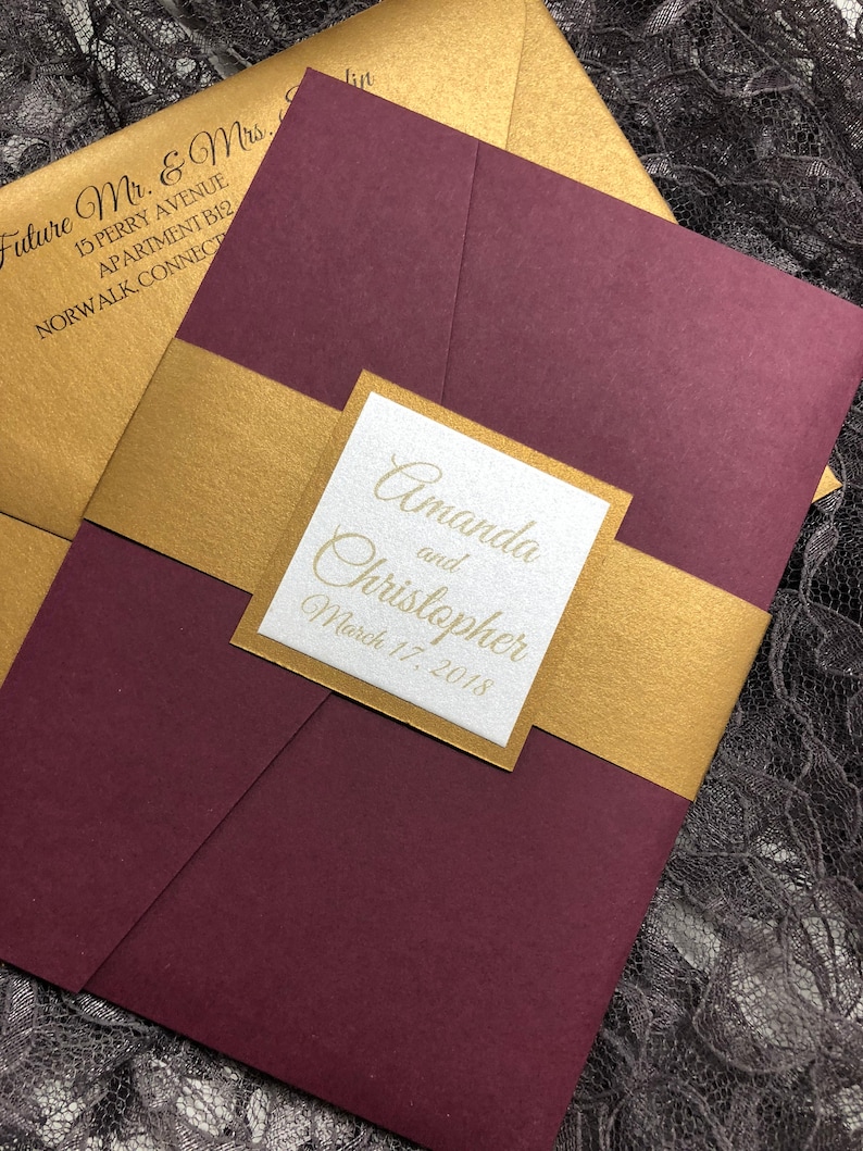 May include: Burgundy and gold wedding invitation with the names Amanda and Christopher and the date March 17, 2018.