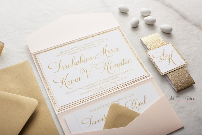 May include: A blush pink and gold wedding invitation with a pocket for a RSVP card. The invitation features the couple's names, "Sarahphina Maria" and "Kevin V. Hampton", in gold script font. The invitation also includes the date and time of the wedding, as well as the location. The RSVP card is a separate piece of paper with a gold script font that says "Seventeenth April".