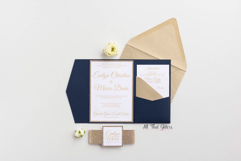 May include: Navy blue wedding invitation with a gold glitter border and gold lettering. The invitation reads "Evelyn Christine & Marco Davis". The invitation is accompanied by a smaller card with the text "Suggested Hotel" and a gold glitter ribbon with the text "Evelyn & Marco" on it.