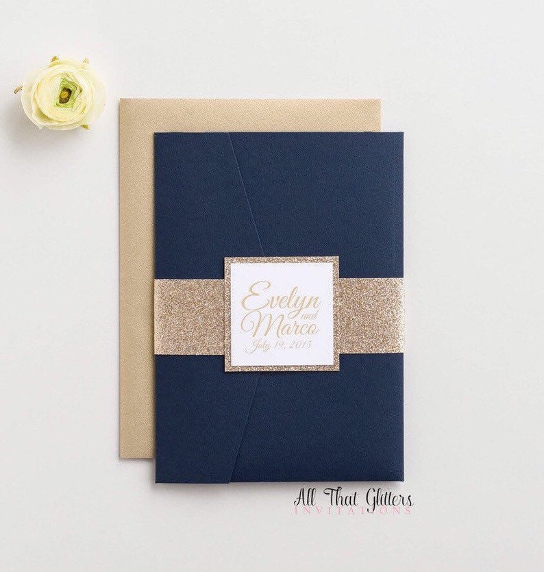 May include: Navy blue wedding invitation with a gold glitter band and a white square with the text "Evelyn and Marco July 19, 2015" in gold script.