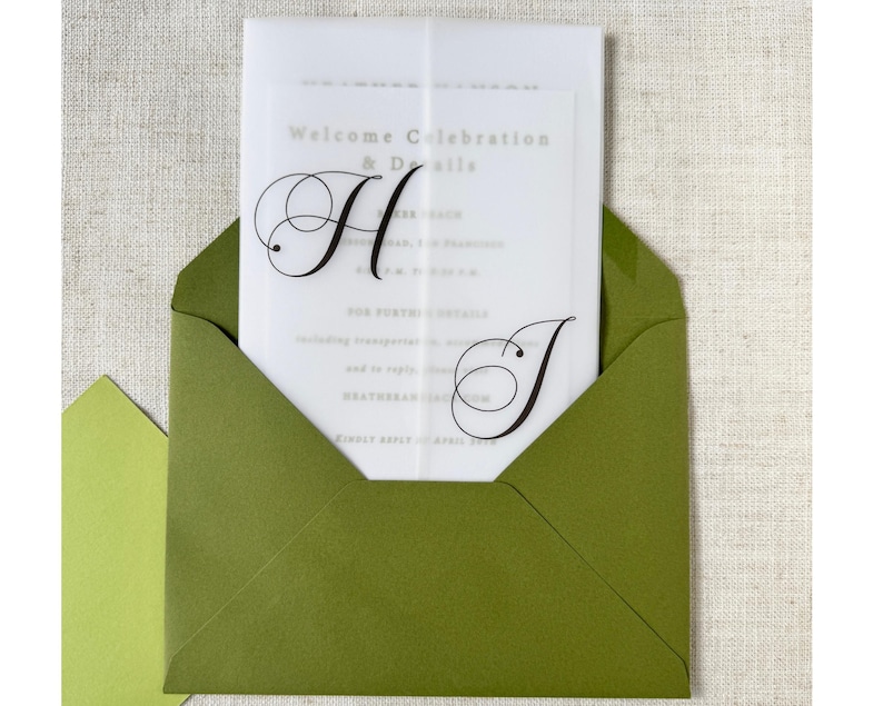 Puede incluir: Un sobre verde oliva contiene una invitaci&oacute;n transl&uacute;cida con el texto "Welcome Celebration & Details". La invitaci&oacute;n presenta las letras estilizadas "H" y "J" en escritura negra. Se ve un sobre m&aacute;s peque&ntilde;o, de color verde claro.