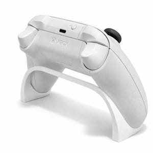 May include: A white Xbox controller resting on a matching white stand. The controller has a black joystick and buttons, with the Xbox logo visible. The stand has a curved design, providing support for the controller.