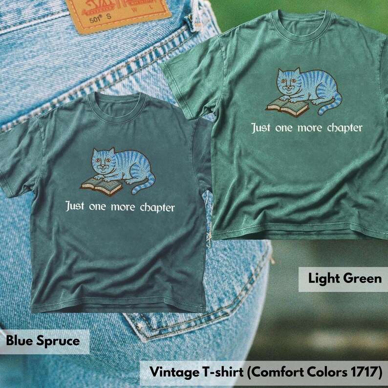 K&ouml;nnte beinhalten: Zwei kurz&auml;rmelige T-Shirts in den Farben Blau-Fichte und Hellgr&uuml;n. Jedes T-Shirt zeigt eine Grafik einer blauen getigerten Katze, die auf einem offenen Buch liegt, mit dem Text "Just one more chapter" in Wei&szlig; unter der Katzenillustration.
