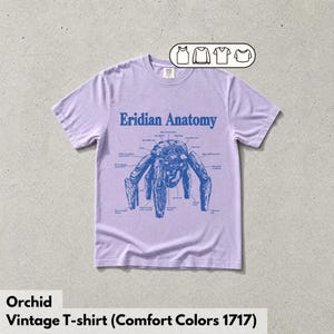 May include: A light purple short-sleeve t-shirt featuring a blue graphic print of a creature labeled Eridian Anatomy with various anatomical lines and text. A small icon box in the top right corner displays four different shirt style options.
