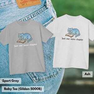K&ouml;nnte beinhalten: Zwei kurz&auml;rmelige T-Shirts, eines in Sportgrau und eines in Aschgrau, mit einer Grafik einer blau gestreiften Katze, die auf einem offenen Buch liegt, und dem Text Just one more chapter in dunkler Schrift unter der Illustration.