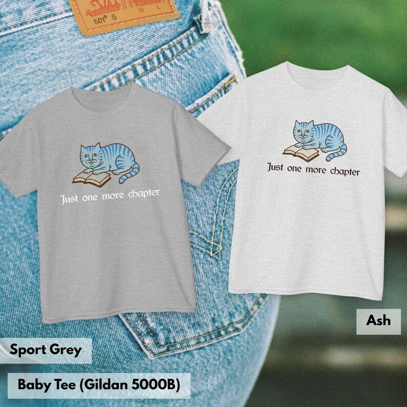 K&ouml;nnte beinhalten: Zwei kurz&auml;rmelige T-Shirts, eines in Sportgrau und eines in Aschgrau, mit einer Grafik einer blau gestreiften Katze, die auf einem offenen Buch liegt, und dem Text Just one more chapter in dunkler Schrift unter der Illustration.