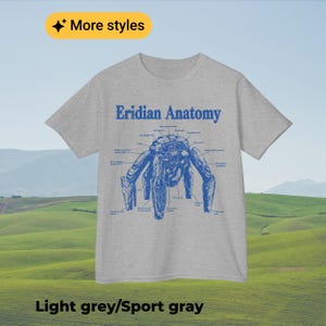 May include: A light grey short-sleeve t-shirt featuring a blue graphic print titled Eridian Anatomy. The design displays a detailed anatomical diagram of a multi-legged creature with various labels pointing to its body parts in blue text.