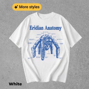 May include: A white short-sleeve t-shirt featuring a blue graphic print titled Eridian Anatomy. The design displays a detailed anatomical diagram of a creature with multiple limbs, including various labels and lines pointing to specific body parts.