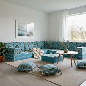 Puede incluir: Sofá seccional turquesa con cojines estampados geométricos. Cojines a juego y una pequeña mesa de centro. Una alfombra neutra y una lámpara de pie completan la decoración de este salón.