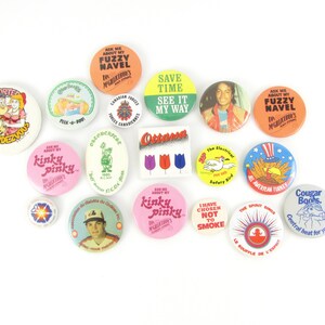 Może przedstawiać: Kolekcja vintage'owych znaczków z różnymi wzorami i hasłami. Niektóre znaczki przedstawiają postacie z kreskówek, a inne mają teksty, takie jak "Save Time See It My Way" i "I Have Chosen Not To Smoke".