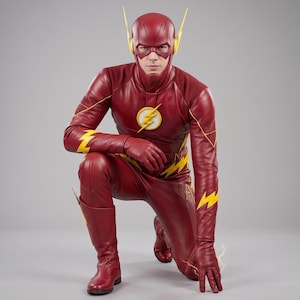 Könnte beinhalten: Ein Ganzkörperkostüm von The Flash, bestehend aus einem dunkelroten, lederartigen Anzug mit gelben Blitzakzenten an Armen, Beinen und dem Brustemblem. Das Outfit umfasst eine passende rote Kapuze mit gelben Ohrenflügeln sowie rote Handschuhe.
