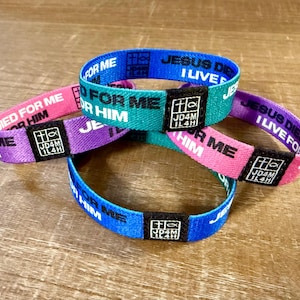 May include: A collection of colorful fabric wristbands. Each band is a different color: blue, green, pink, and purple. The text "JESUS DIED I LIVE FOR HIM" is printed on the bands, along with a religious symbol and the text "JD4M IL4H".