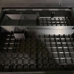 a black plastic container with multiple compartments, designed to hold and organize various items.