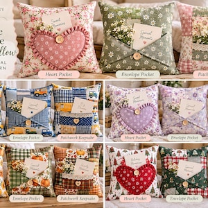 Op de afbeelding: Een collectie vierkante decoratieve kussens met drie verschillende ontwerpen: een hartvormige zak, een envelopzak en een patchworkzak. Elk kussen is versierd met een kleine houten knoop en bevat een kaartje met tekst.