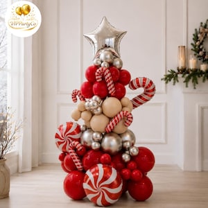 Puede incluir: Una escultura de globos con forma de árbol de Navidad que presenta globos rojos, plateados y beige. Incluye globos de aluminio con forma de bastón de caramelo, globos redondos con patrón de menta y una gran estrella plateada en la cima.