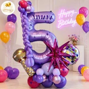 Puede incluir: Un gran globo de aluminio morado con forma de número 5 y el nombre VIVIANA impreso, decorado con una guirnalda de globos morados trenzados, un globo de micrófono dorado, un globo de estrella y un globo de bola de discoteca.