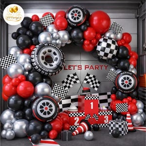 May include: A racing-themed party decoration set with a balloon arch in black, red, and silver. The arch features tire-shaped balloons, checkered flags, and the text "LET'S PARTY". Additional decorations include numbered boxes and a cone.