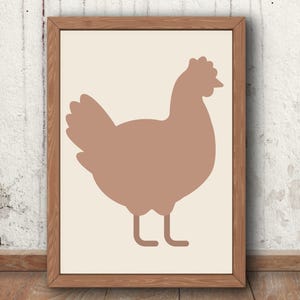 Puede incluir: Una lámina de arte enmarcada que presenta la silueta sólida de una gallina en color malva apagado, centrada sobre un fondo crema claro. La obra está contenida en un marco de madera de tono medio sencillo con textura de veta visible.