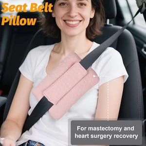 Könnte beinhalten: Ein rosa Sicherheitsgurtkissen befindet sich an einem schwarzen Sicherheitsgurt. Der Text "Seat Belt Pillow" ist in Orange und Gelb. Der Text "For mastectomy and heart surgery recovery" befindet sich in einem grauen Feld.