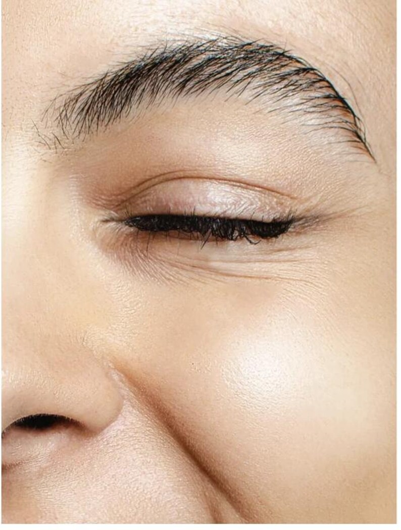 May include: Close-up of a person's closed eye, showcasing detailed skin texture and dark eyelashes. The eyebrow is well-defined with individual hairs visible. The skin has a smooth, healthy appearance, with subtle wrinkles around the eye.