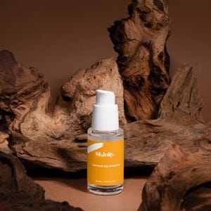 May include: A clear glass bottle with a white pump top and a bright yellow label. The label reads "Skinity Caffeine Gel Booster" and contains 30 mL / 1.01 fl oz. The bottle is set against a backdrop of brown wood.