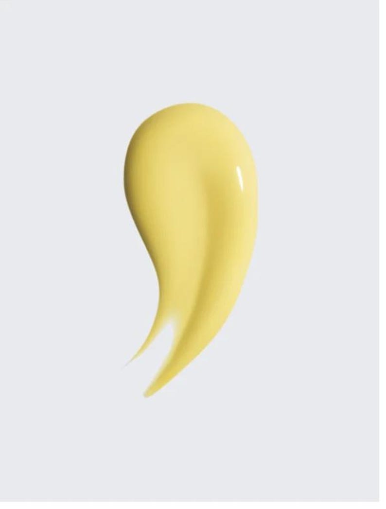 K&ouml;nnte beinhalten: Ein glattes, gelbes Kosmetikprodukt, m&ouml;glicherweise eine Creme oder Lotion, wird vor einem hellgrauen Hintergrund gezeigt. Das Produkt hat eine geschwungene, tropfenf&ouml;rmige Form mit gl&auml;nzendem Glanz, was auf eine reichhaltige Textur hindeutet.