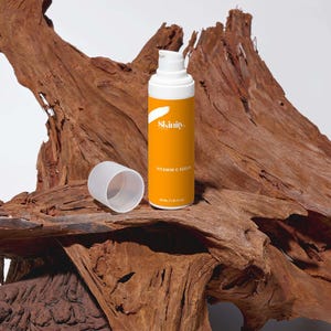 K&ouml;nnte beinhalten: Eine orange-wei&szlig;e Vitamin-C-Serumflasche mit dem Markennamen "Skinity" und dem Text "Vitamin C Serum" auf dem Etikett. Die Flasche enth&auml;lt 30 ml. Der Deckel ist abgenommen und liegt neben der Flasche. Der Hintergrund ist ein St&uuml;ck strukturiertes Holz.