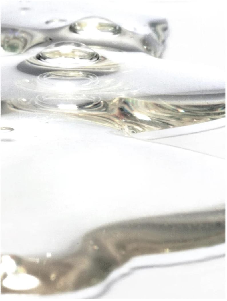 May include: Abstract image of clear, liquid droplets with a reflective, metallic sheen. The droplets are arranged in a pattern, creating a sense of depth and texture against a white background. The image has a soft focus.