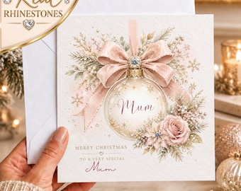 May include: A square Christmas greeting card featuring a central glass ornament illustration with a pink ribbon bow, a rose, and pine branches. The text reads Mum, Merry Christmas, and To a very special Mum. The design includes real rhinestones.