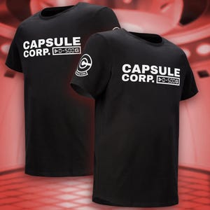 May include: Two black t-shirts with white text that reads "CAPSULE CORP." and "0-500G." One shirt has a logo on the sleeve. The shirts are displayed against a red and white background.