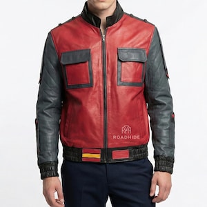 Puede incluir: Chaqueta de cuero roja y gris con cuello negro y cierre de cremallera. La chaqueta tiene dos bolsillos delanteros, mangas grises acolchadas y una franja negra y amarilla en la cintura. El logotipo de Roadhide es visible en la parte inferior derecha.