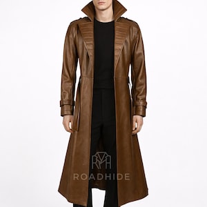 May include: A brown leather trench coat with a wide collar and a belted waist. The coat has a long length, reaching the ankles, and features detailed stitching and design elements. The brand name "ROADHIDE" is visible at the bottom.