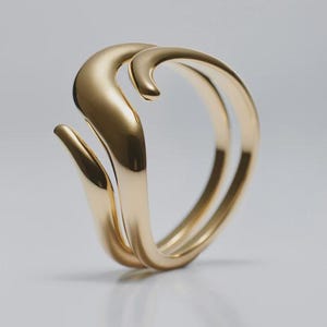 Puede incluir: Un anillo de oro pulido con un diseño fluido y abierto que presenta dos bandas curvas superpuestas que crean una silueta ondulada. La superficie metálica es lisa y reflectante, captando la luz para resaltar su forma continua y orgánica.