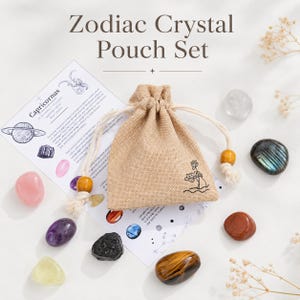 Puede incluir: Un juego de bolsas de cristales del zodiaco con una bolsa con cordón beige, varios cristales coloridos y una tarjeta de información de Capricornio. La bolsa tiene un pequeño diseño floral. Los cristales incluyen piedras rosas, moradas, amarillas y marrones.