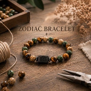 Peut inclure: Un bracelet du zodiaque perlé avec une pièce maîtresse rectangulaire foncée. Le bracelet présente un mélange de perles marron, vertes et beiges. Le texte "ZODIAC BRACELET" est affiché au-dessus du bracelet.
