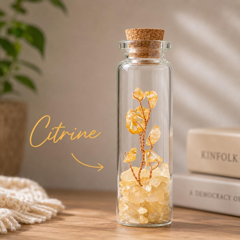 May include: A clear glass bottle with a cork stopper filled with yellow citrine crystals. A wire structure with citrine crystal accents is inside the bottle. The word "Citrine" is written in cursive on the left side of the image.