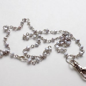 May include: A silver chain necklace with a silver clasp. The chain is made of small silver beads and is about 30 inches long.