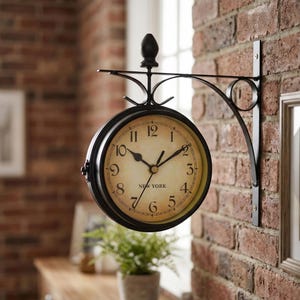 May include: A black, double-sided wall clock with a vintage design. The clock face is cream-colored with black Roman numerals and the word "NEW YORK" at the bottom. The clock is mounted on a black metal bracket against a brick wall.
