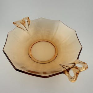 May include: A white ceramic mug with a black handle and the text "But First, Coffee" in a bold, black font. The mug is set against a blurred background, suggesting a cozy setting.