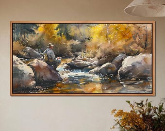 May include: A watercolour painting depicting a person fishing in a river. The artwork shows a tranquil scene with a fisherman seated on a rock, surrounded by trees and water. The painting is framed in a wooden frame.