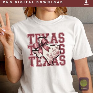 May include: White t-shirt with a maroon design featuring the word "TEXAS" stacked three times. The center of the design is a map of Texas, adorned with floral patterns and a pink bow. The words "PNG DIGITAL DOWNLOAD" are at the top.